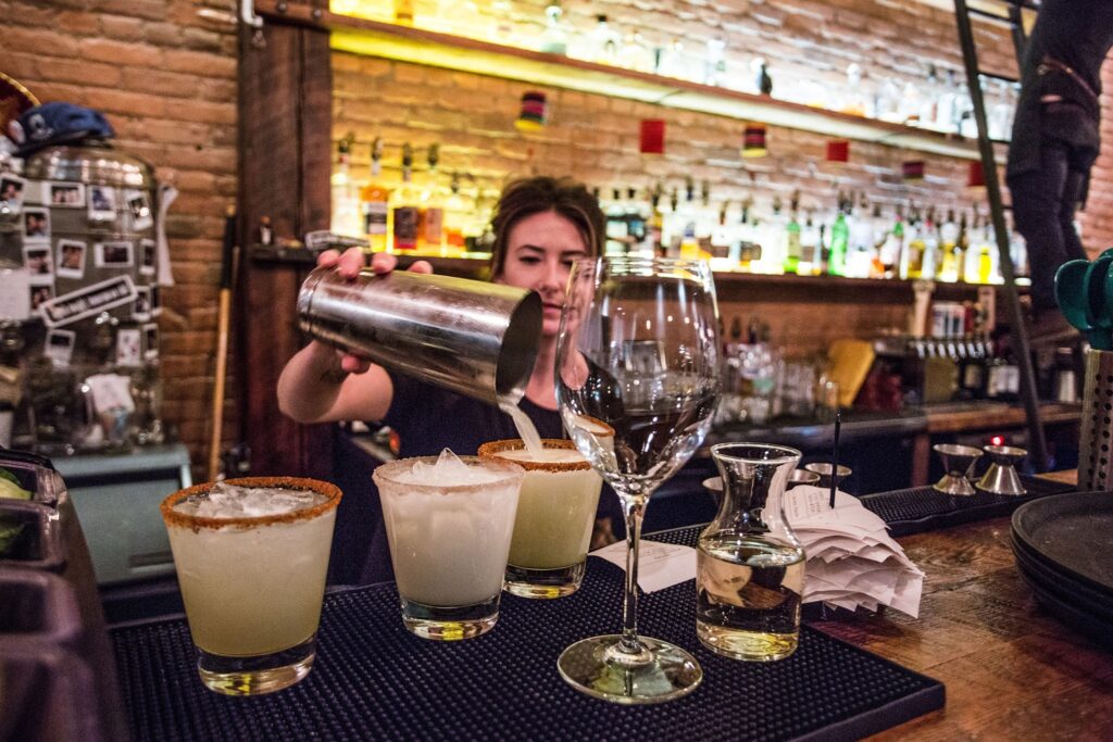 It is the restaurant's interior; there are liquor bottles for the bartender at the back wall to use. The bartender is pouring alcoholic beverages. 